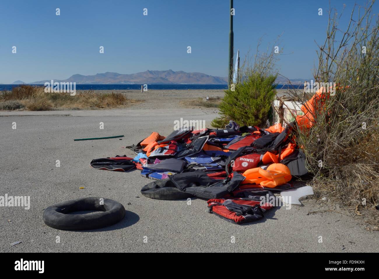 Abandoned lifejackets and rubber rings used by migrants on their journey by small boats to Greece from Turkey on the beach near Stock Photo