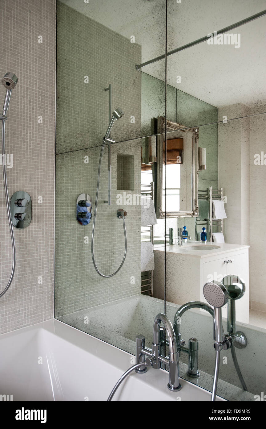 Mirrored wall above bath with chrome shower and tap fittings Stock