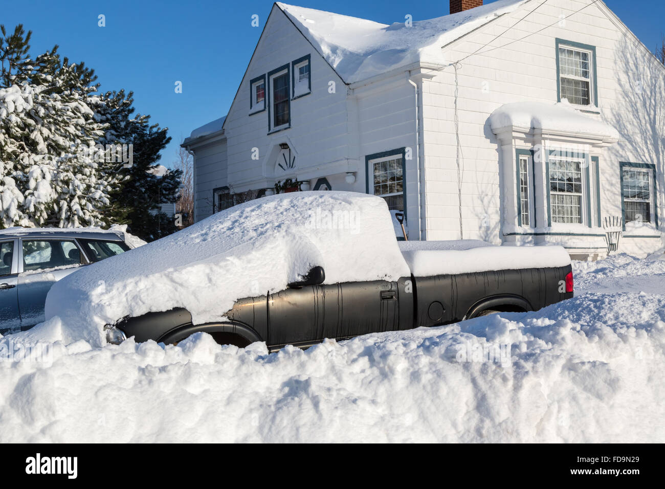 Piles of snow bury a truck and home in a North American suburb. Stock Photo