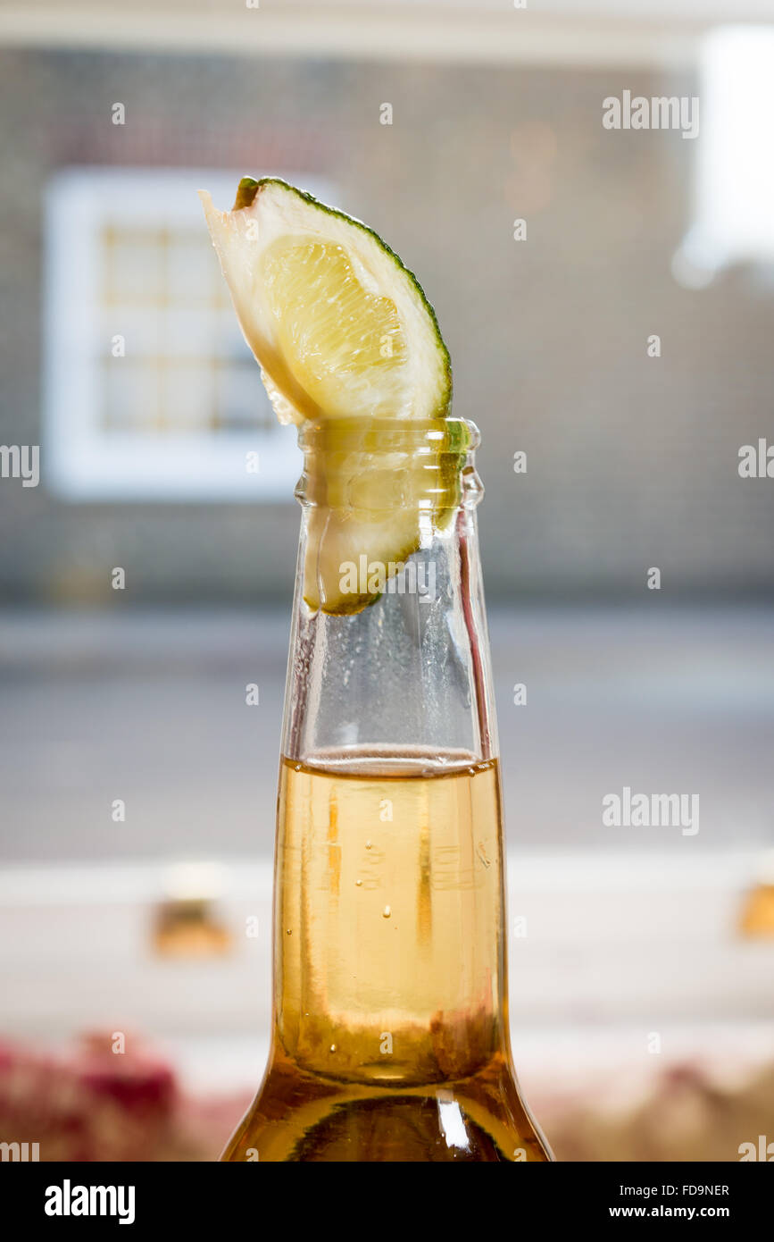 A lager bottle with a piece of lime in the bottle neck ready to drink. A lager and lime. Stock Photo