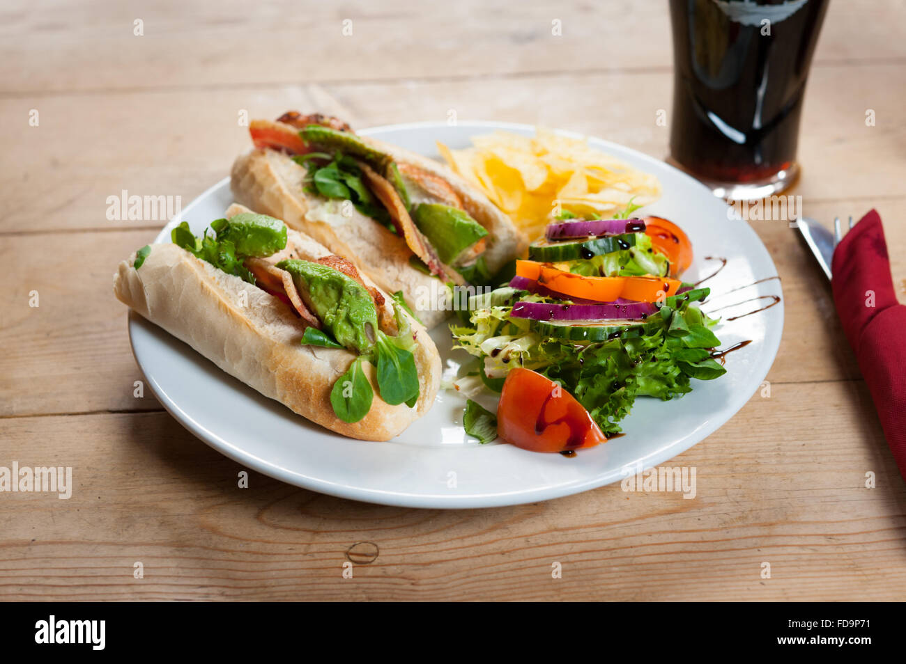 A Bacon lettuce and tomato sandwich and salad on a plate on a wooden