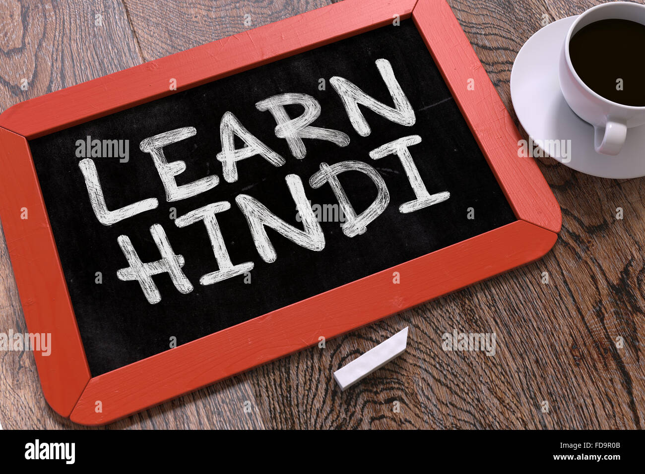 Learn Hindi Handwritten by White Chalk on a Blackboard. Composition with Small Red Chalkboard and Cup of Coffee. Top View. Stock Photo
