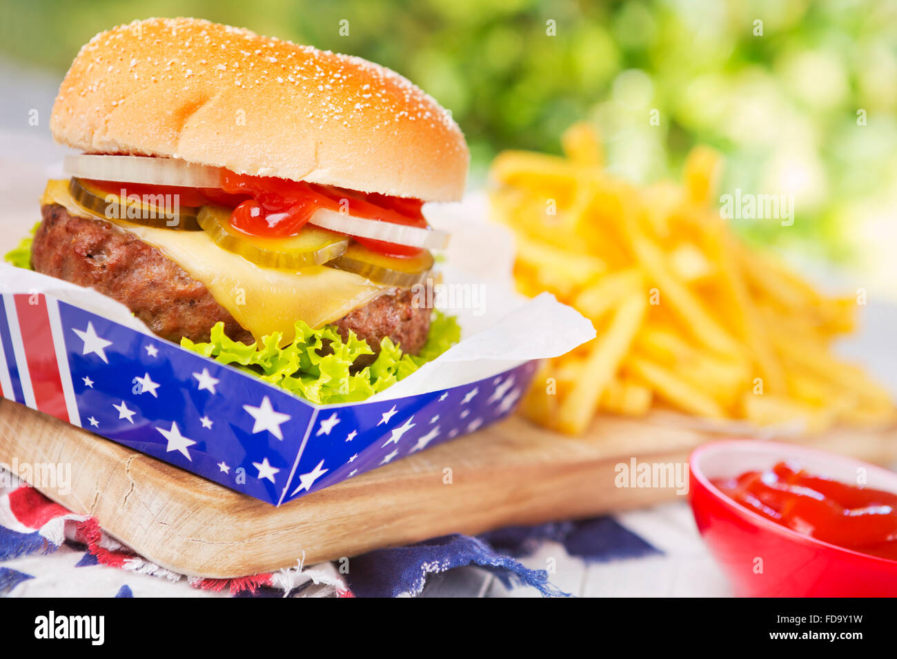 A tasty burger with fries on an outdoor table. Stock Photo