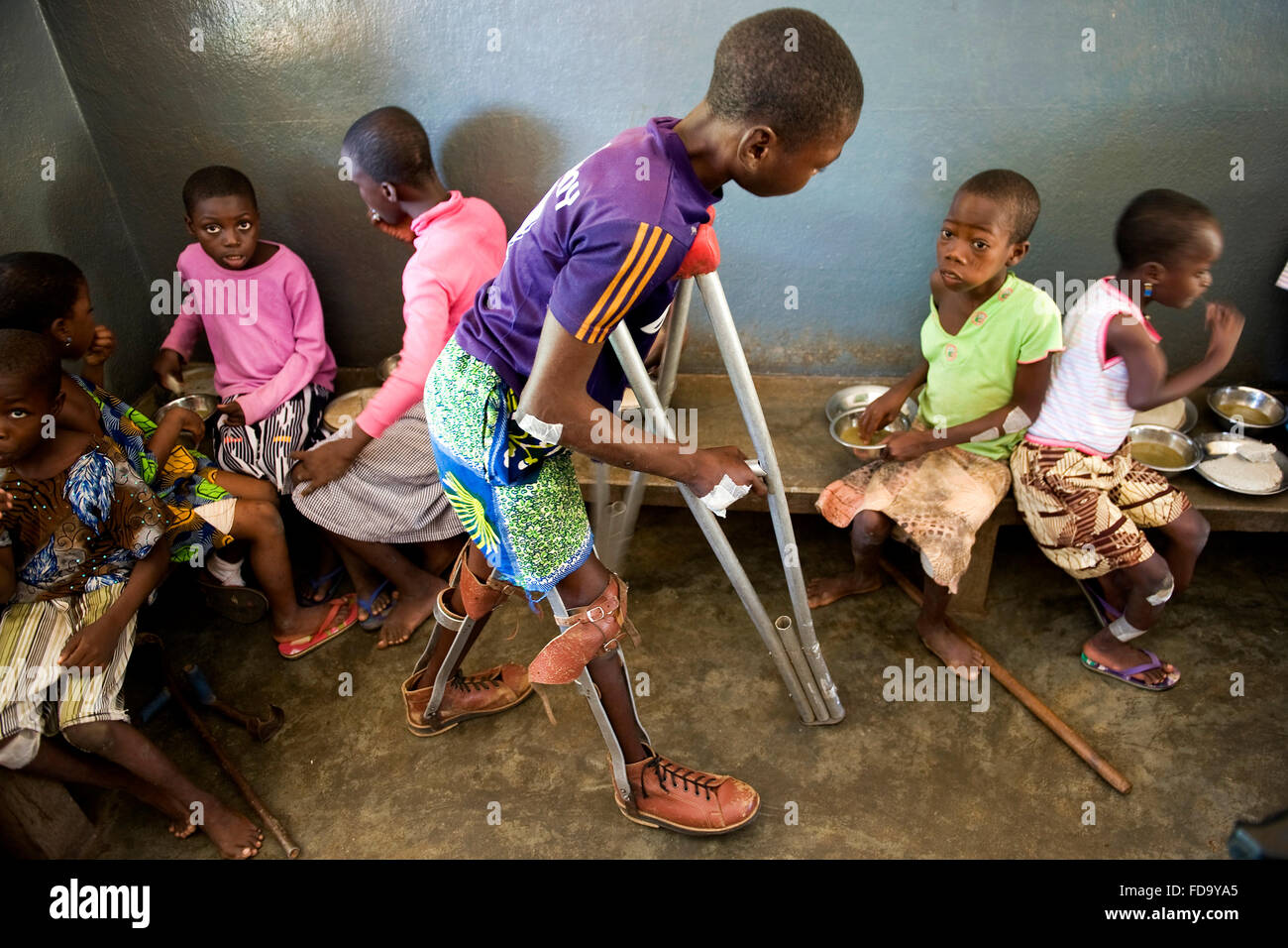 A young man with crutches and prosthetic heads to chair the religious center of Don Orione in northern Togo for children and you Stock Photo