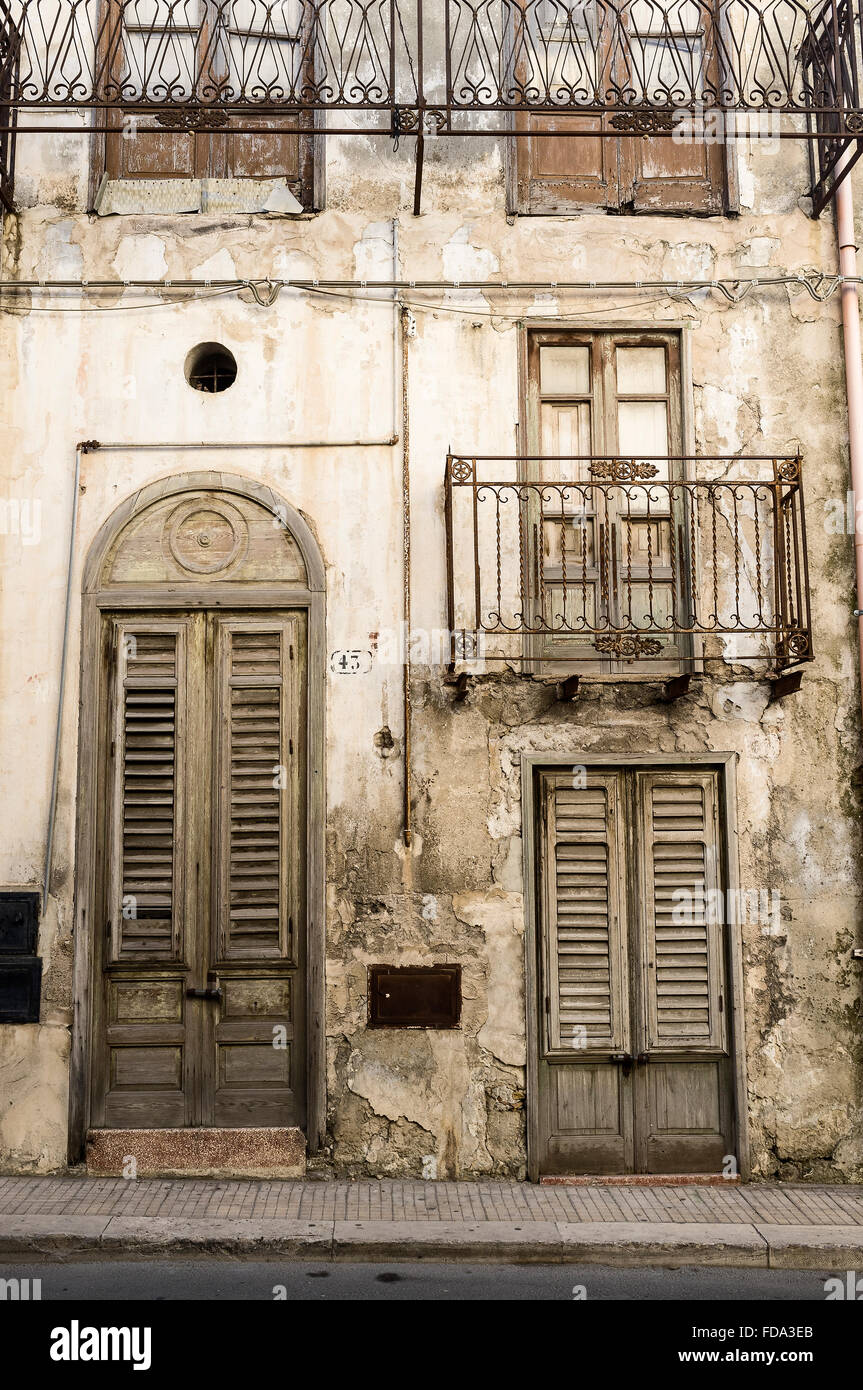 Wooden front door and wrought iron balcony of townhouse exterior in Balestrate, Province of Palermo, Sicily, Italy Stock Photo