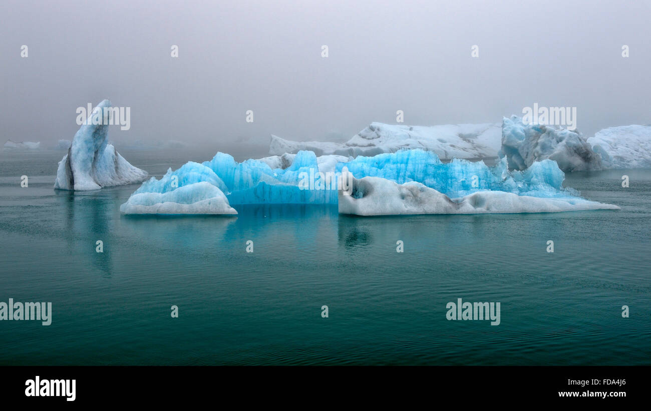 Drifting blue icebergs in the Jökulsárlón glacier lagoon in fog, Southern Region, Iceland Stock Photo