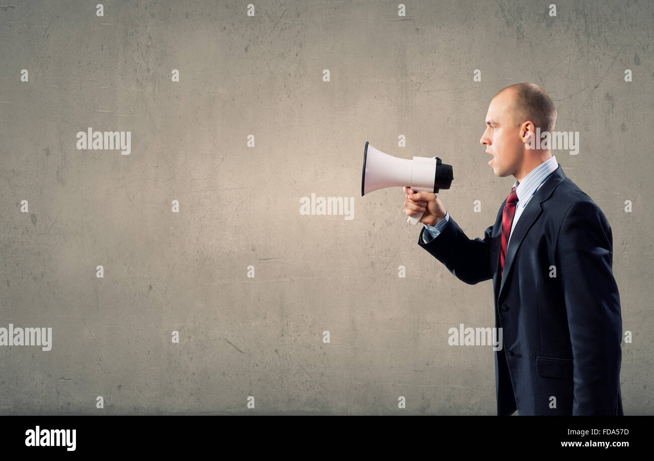 Businessman using megaphone to scream agressively at woman Stock Photo