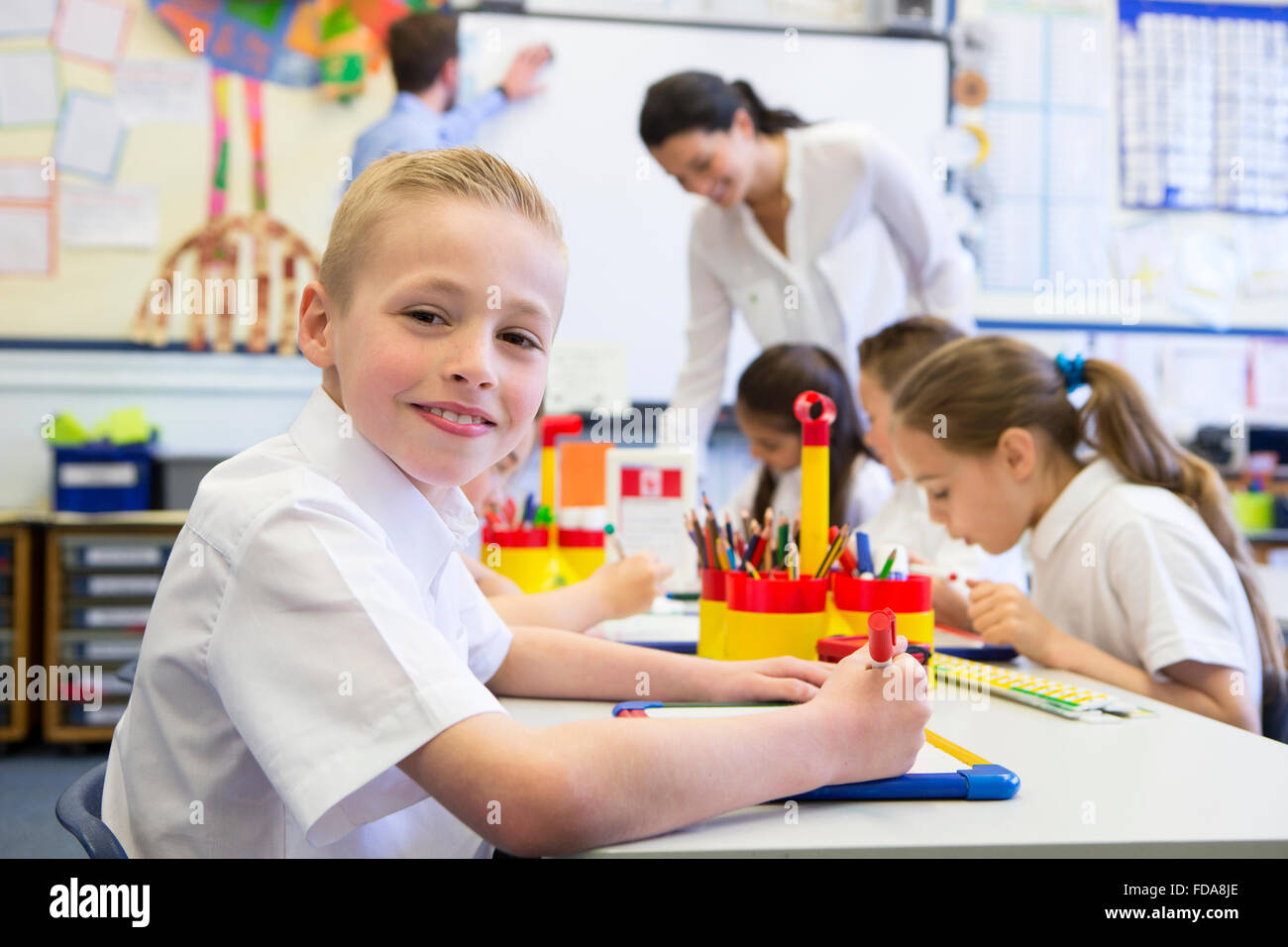 Portrait of a cute young schoolboy smiling at the camera while sitting ...