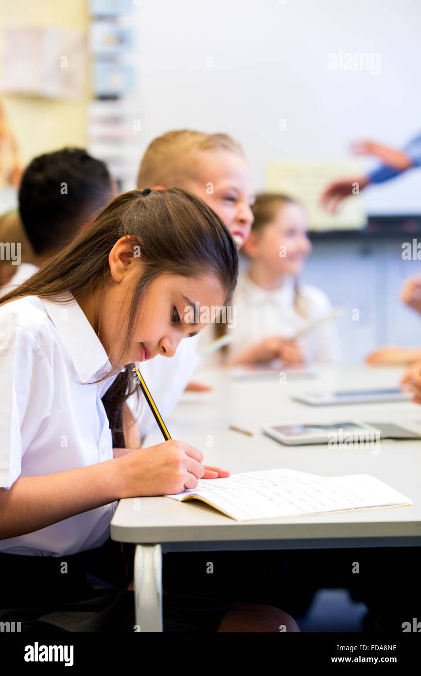 Schoolgirl sits at her desk while working . Stock Photo
