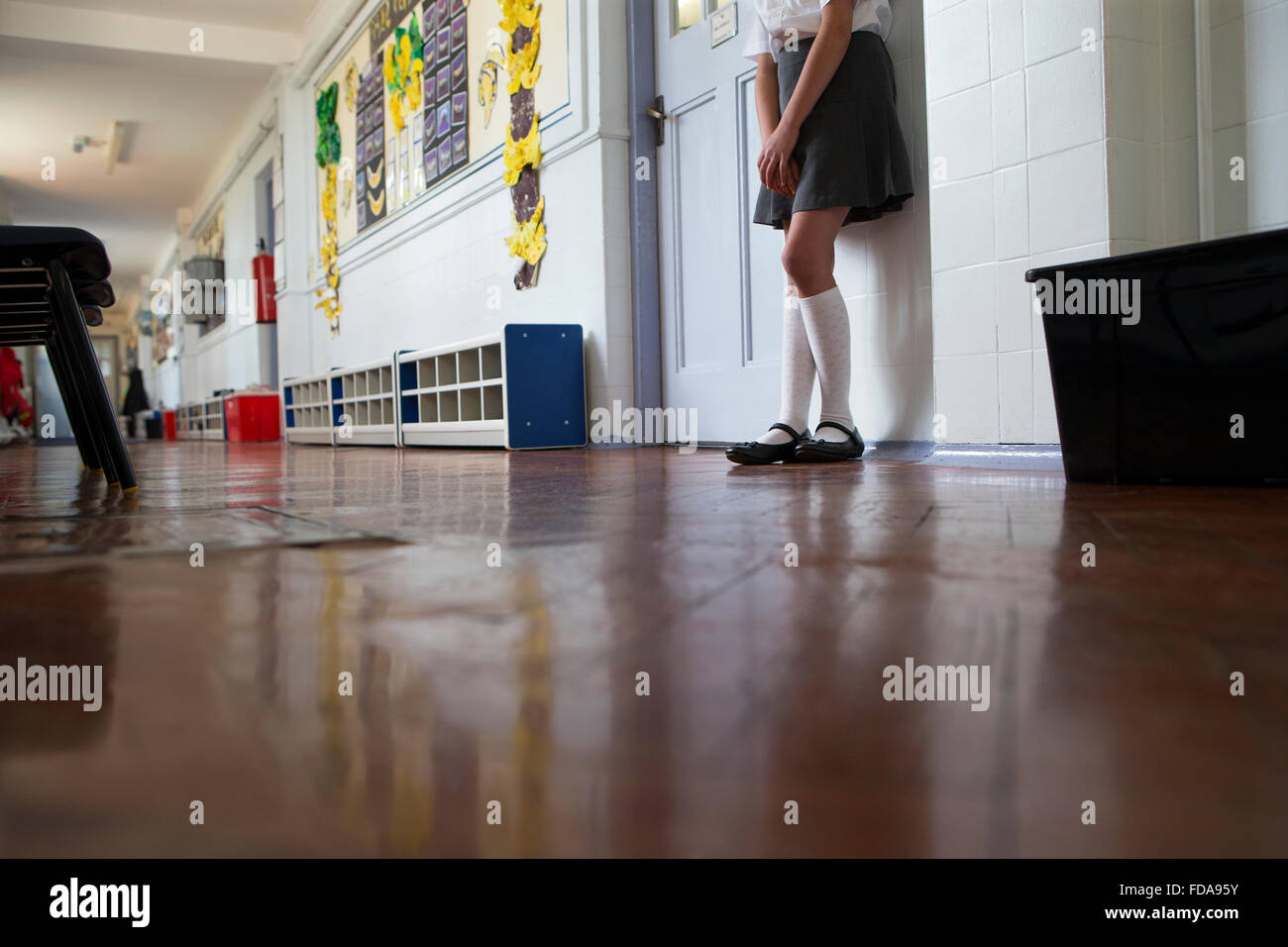 Naughty school girl stands in the corridor after being sent out of class. Stock Photo