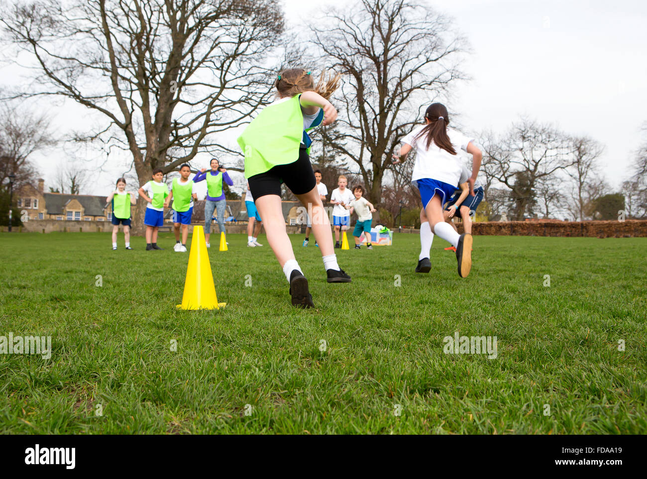 School children wearing sports uniform running around cones during a physical education session. Stock Photo