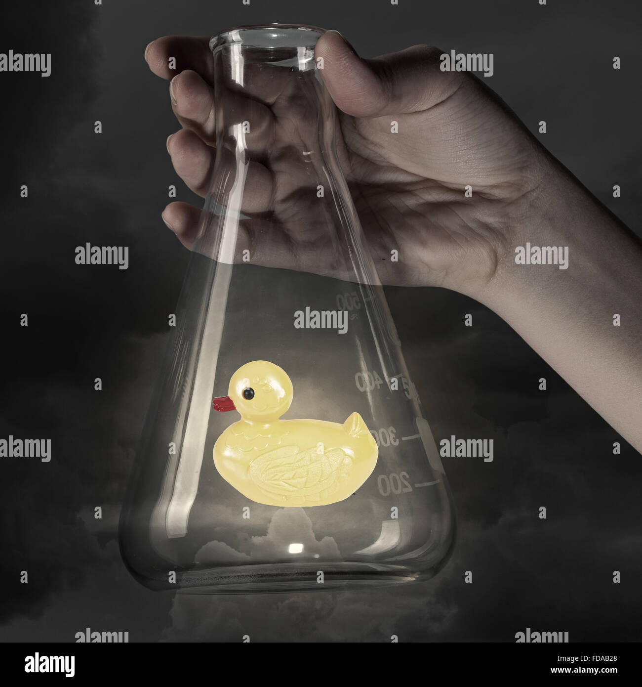 Human hand holding glass tube with yellow rubber duck toy Stock Photo