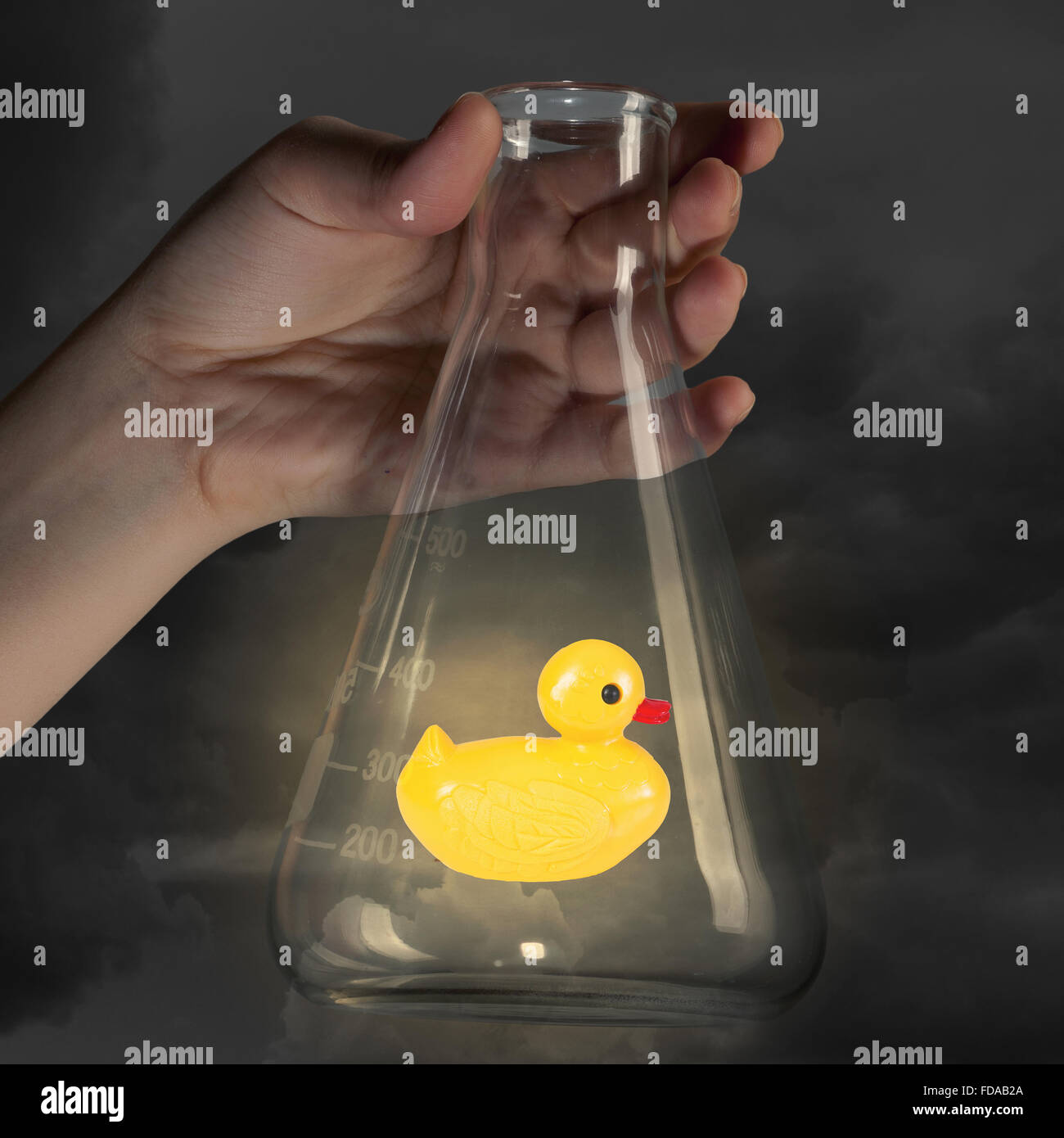 Human hand holding glass tube with yellow rubber duck toy Stock Photo