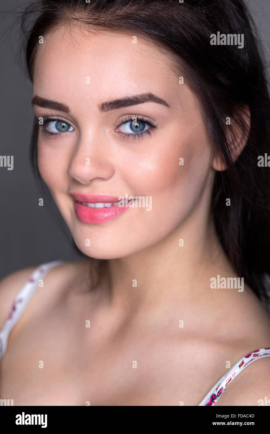 Portrait of a young woman taken in a studio. She is looking at the camera and smiling. Stock Photo