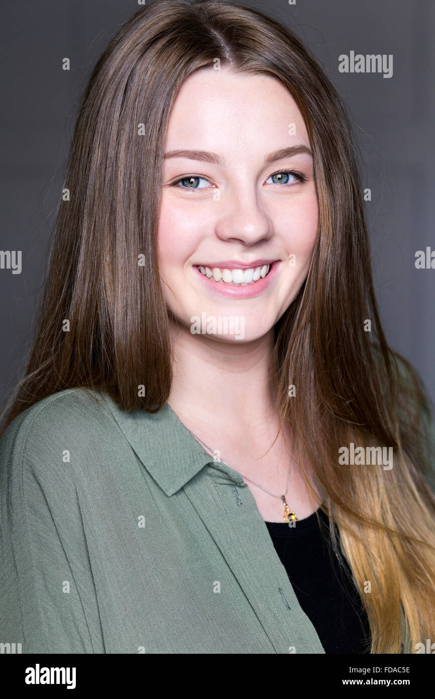 Headshot of a beautiful young woman taken in a studio on a grey