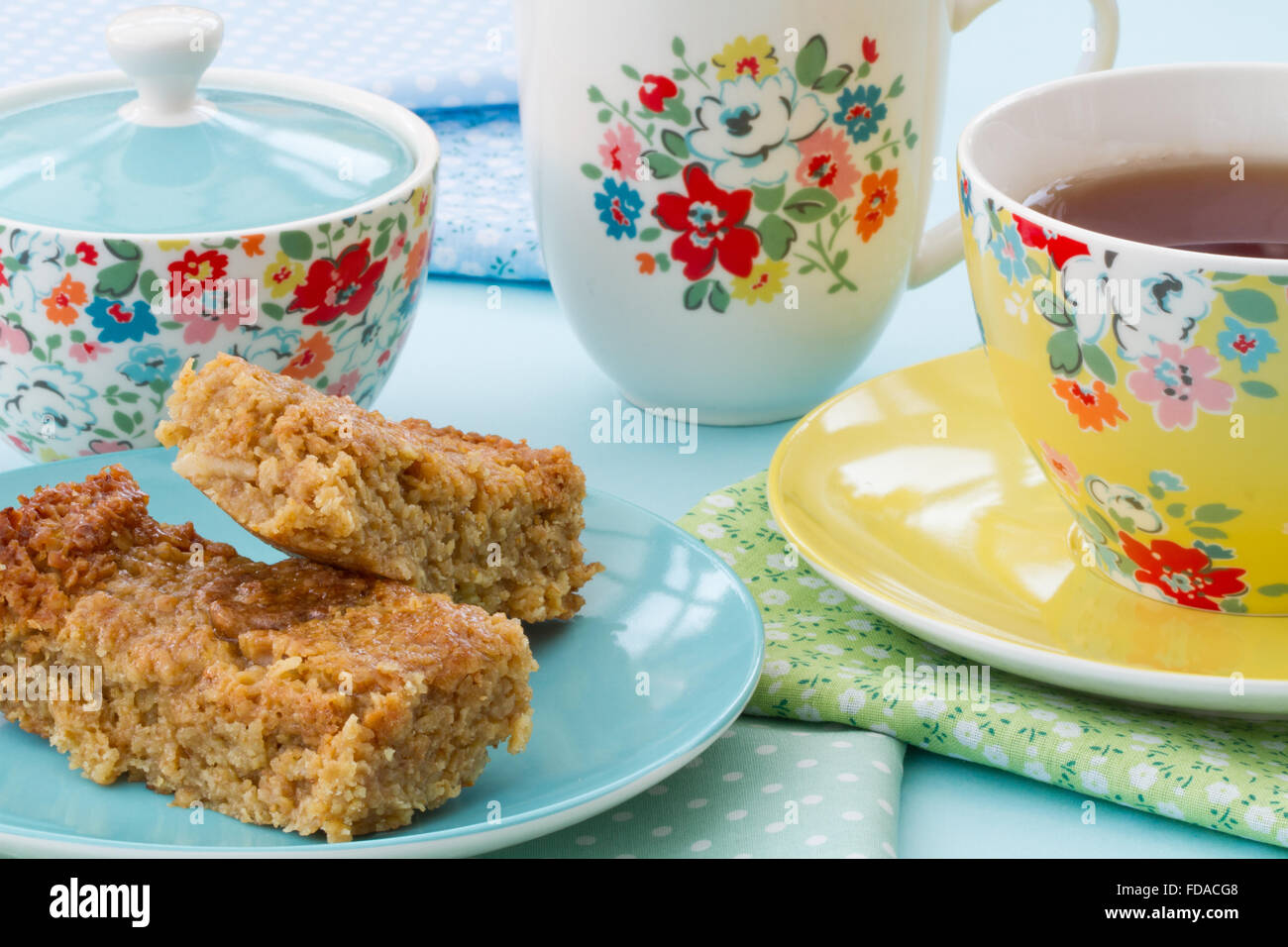 Afternoon tea or high tea of cake and a cup of tea in floral crockery.  Flapjack and tea in a flowered cup and saucer as a snack Stock Photo