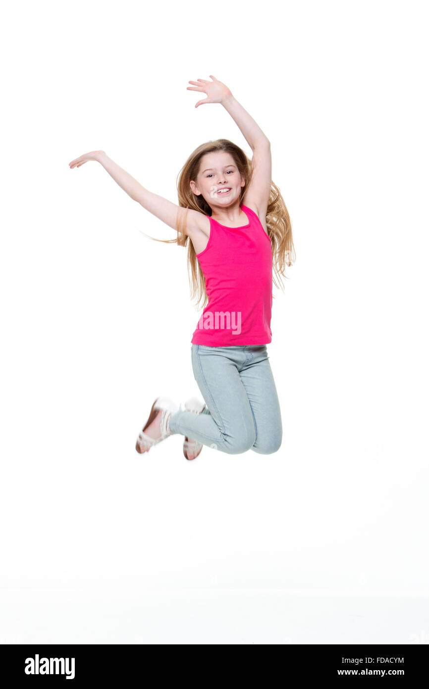 Portrait of a happy little girl jumping in the air against a white