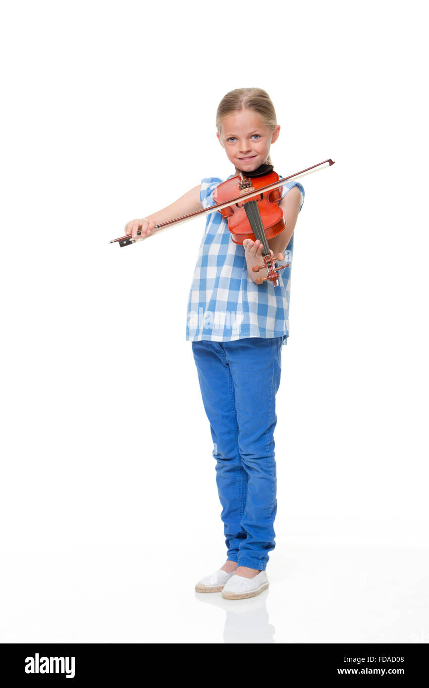 Little girl playing a violin on a white background. She is looking at the camera and smiling. Stock Photo