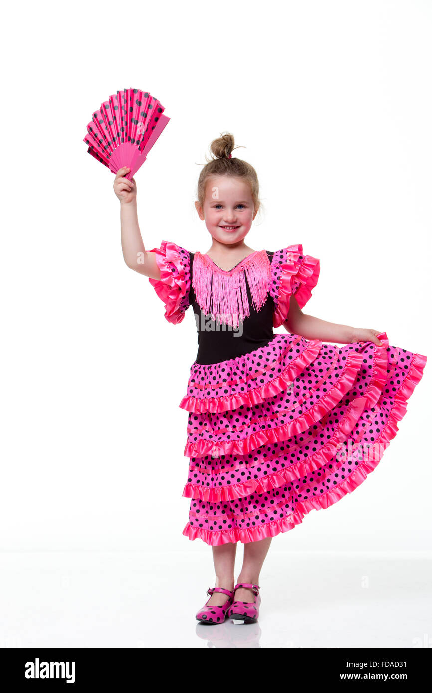 Young girl dressed as a flamenco dancer with a white background. The girl is looking at the camera and smiling. Stock Photo