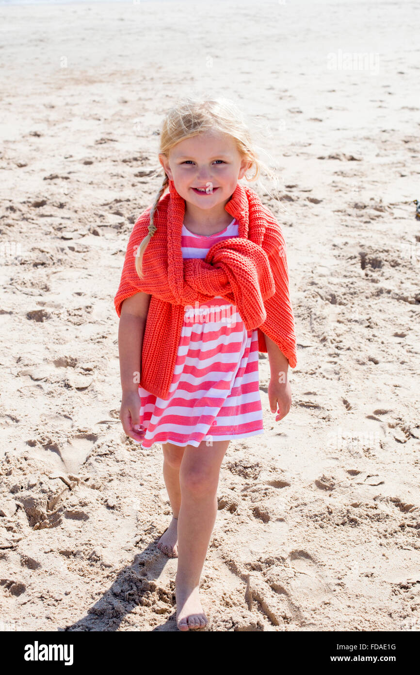 Little girl on the beach smiling at the camera. Stock Photo