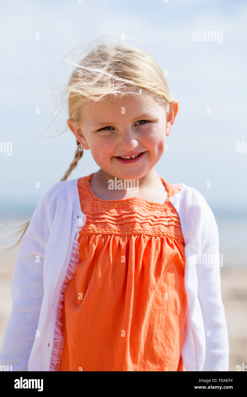 Portrait of a beautiful little girl outdoors. She is wearing casual clothing and smiling at the camera. Stock Photo