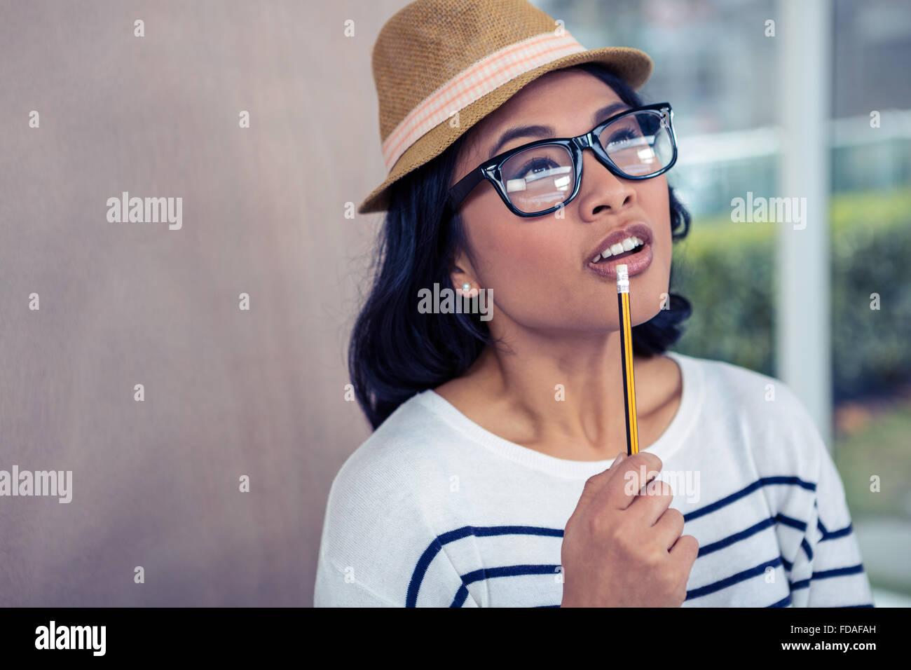 Thoughtful Asian woman with pencil on mouth Stock Photo - Alamy