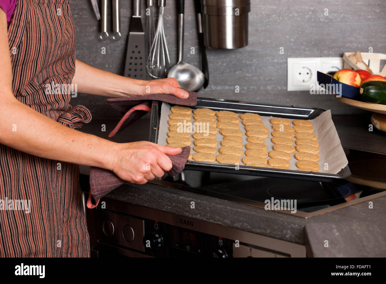 Woman taking finished cookies out of oven Stock Photo