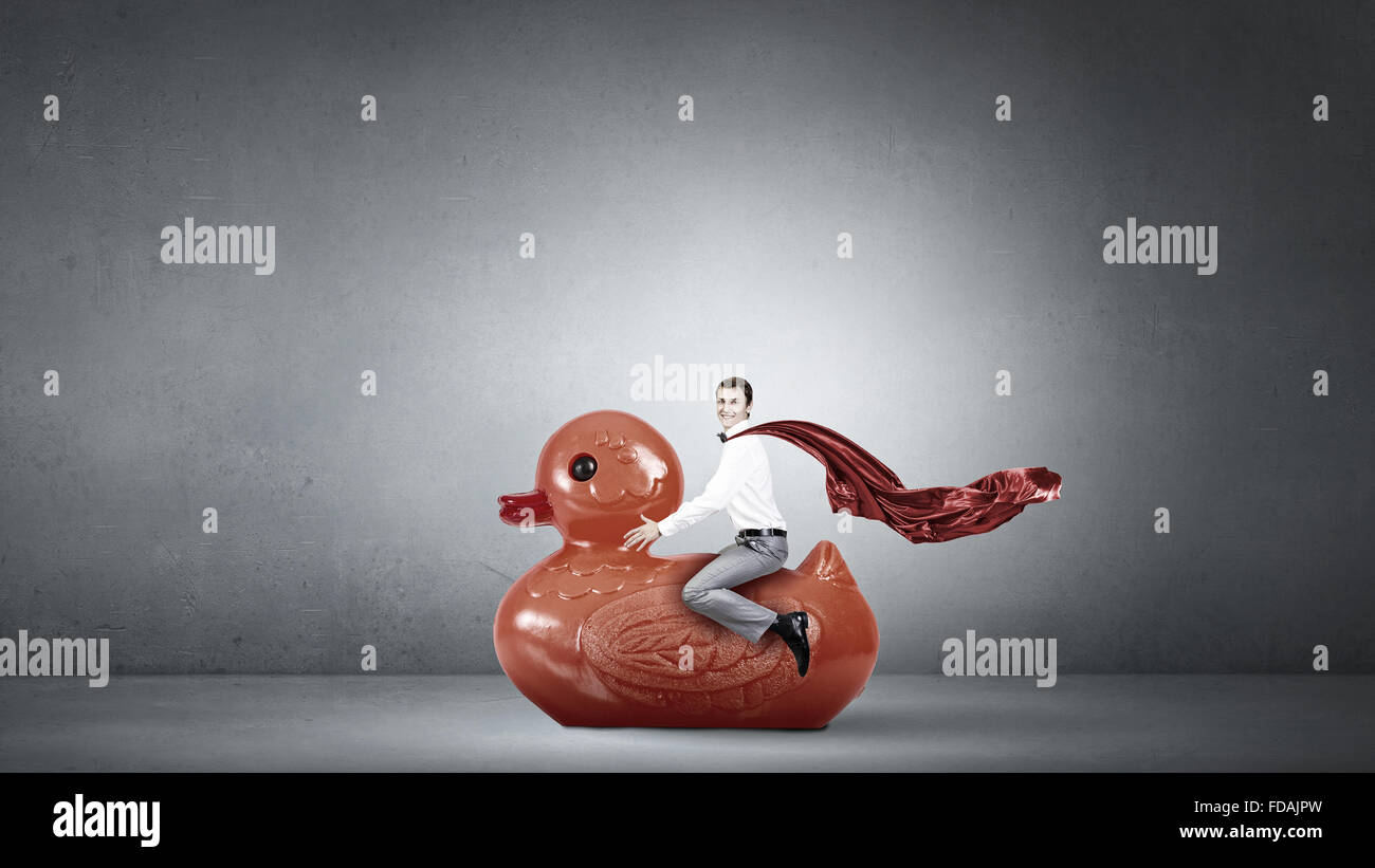Young happy businessman riding red rubber duck Stock Photo - Alamy