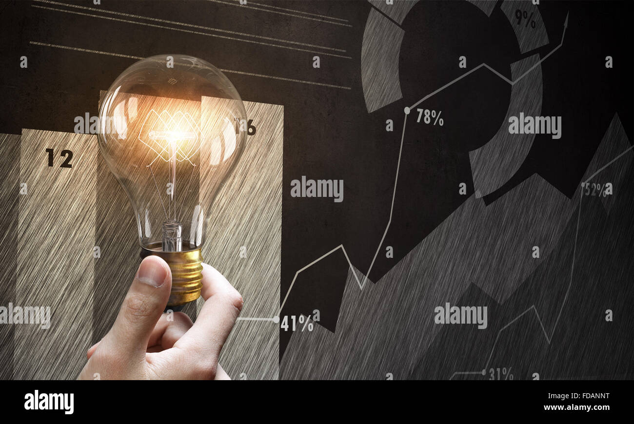 Male hand holding light bulb on background of diagrams and graphs Stock ...