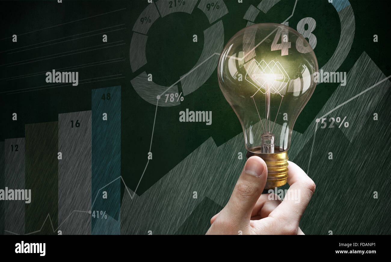 Male hand holding light bulb on background of diagrams and graphs Stock ...