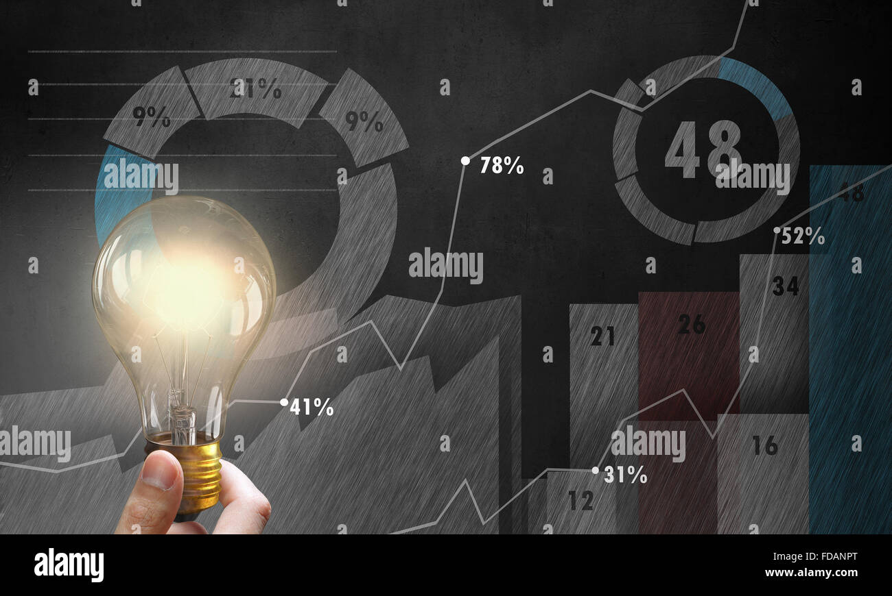Male hand holding light bulb on background of diagrams and graphs Stock ...