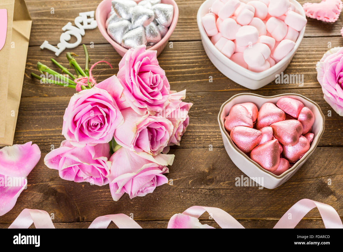 Pink roses with chocolates on rustic wood table Stock Photo - Alamy