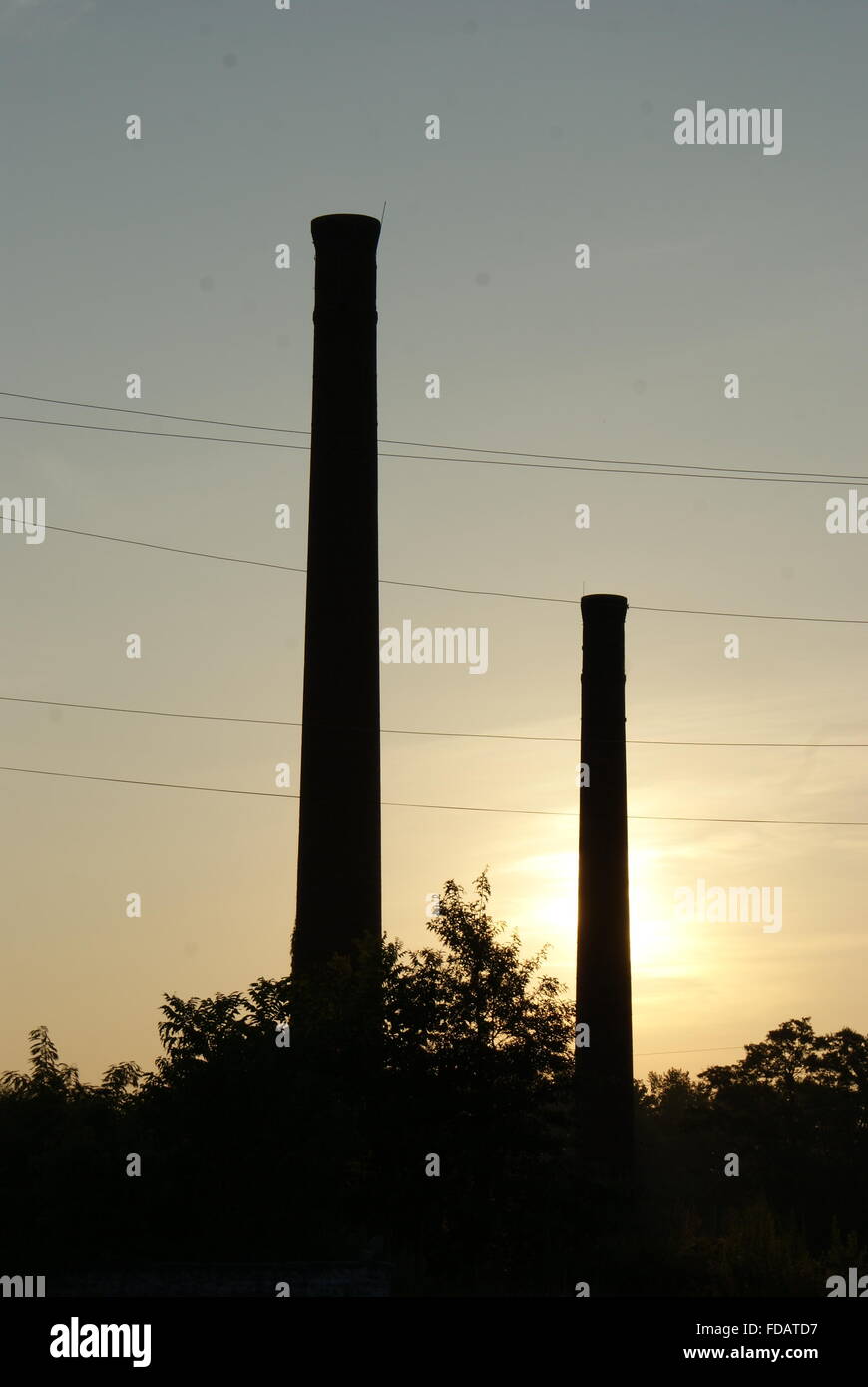 Sunrise with two old abandoned factory smoke stacks in a small industrial Georgia town. Stock Photo