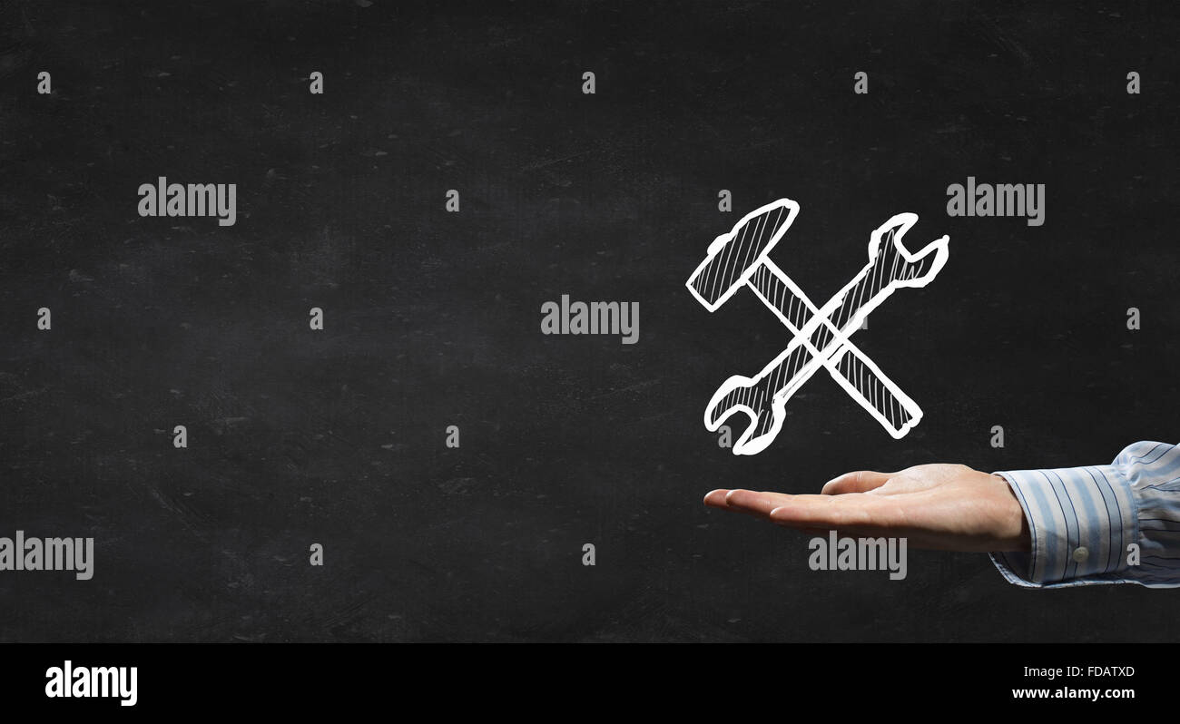 Businessman&rsquo;s hand holding tools over gray background Stock Photo - Alamy