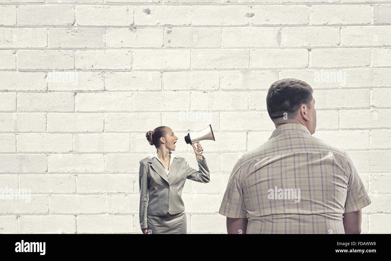 Furious woman screaming agressively in megaphone at man Stock Photo