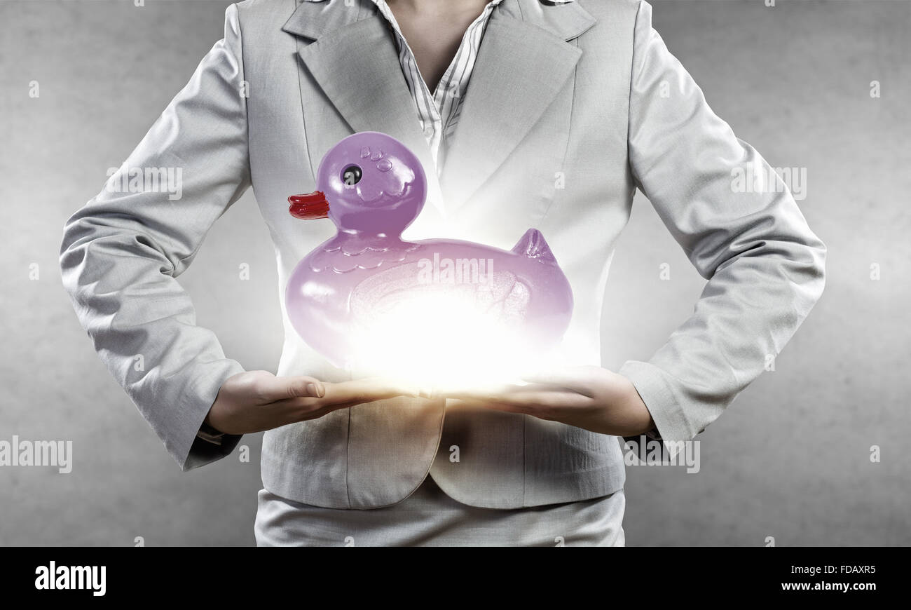 Businesswoman holding in hands yellow toy rubber or plastic duck Stock Photo