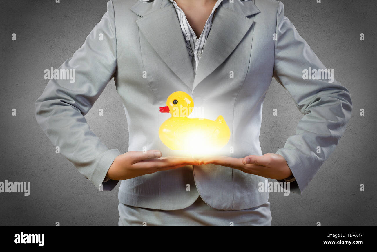 Businesswoman holding in hands yellow toy rubber or plastic duck Stock Photo
