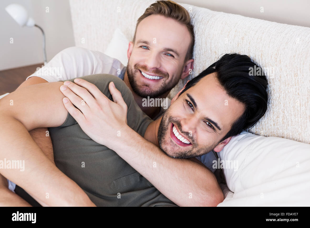 Happy gay couple lying on bed Stock Photo - Alamy