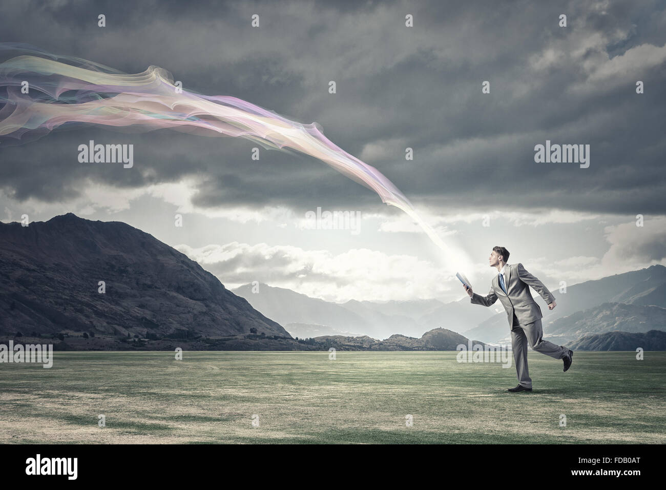 Young businessman running with book in hand Stock Photo