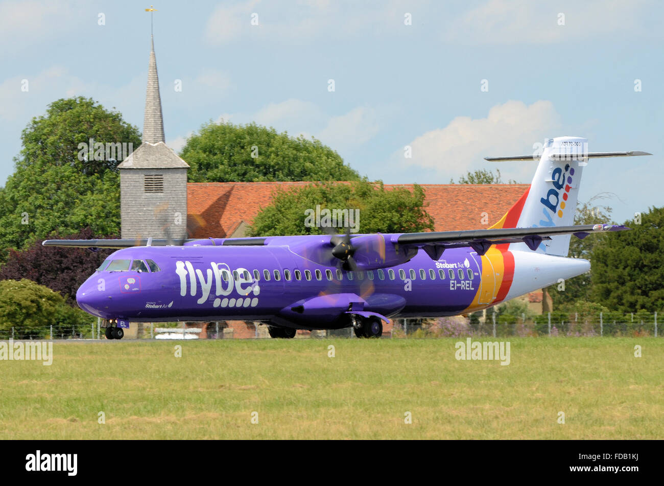 Flybe ATR 72 EI-REL taxiing passed St. Lawrence and All Saints church which is on the edge of London Southend airport perimeter Stock Photo