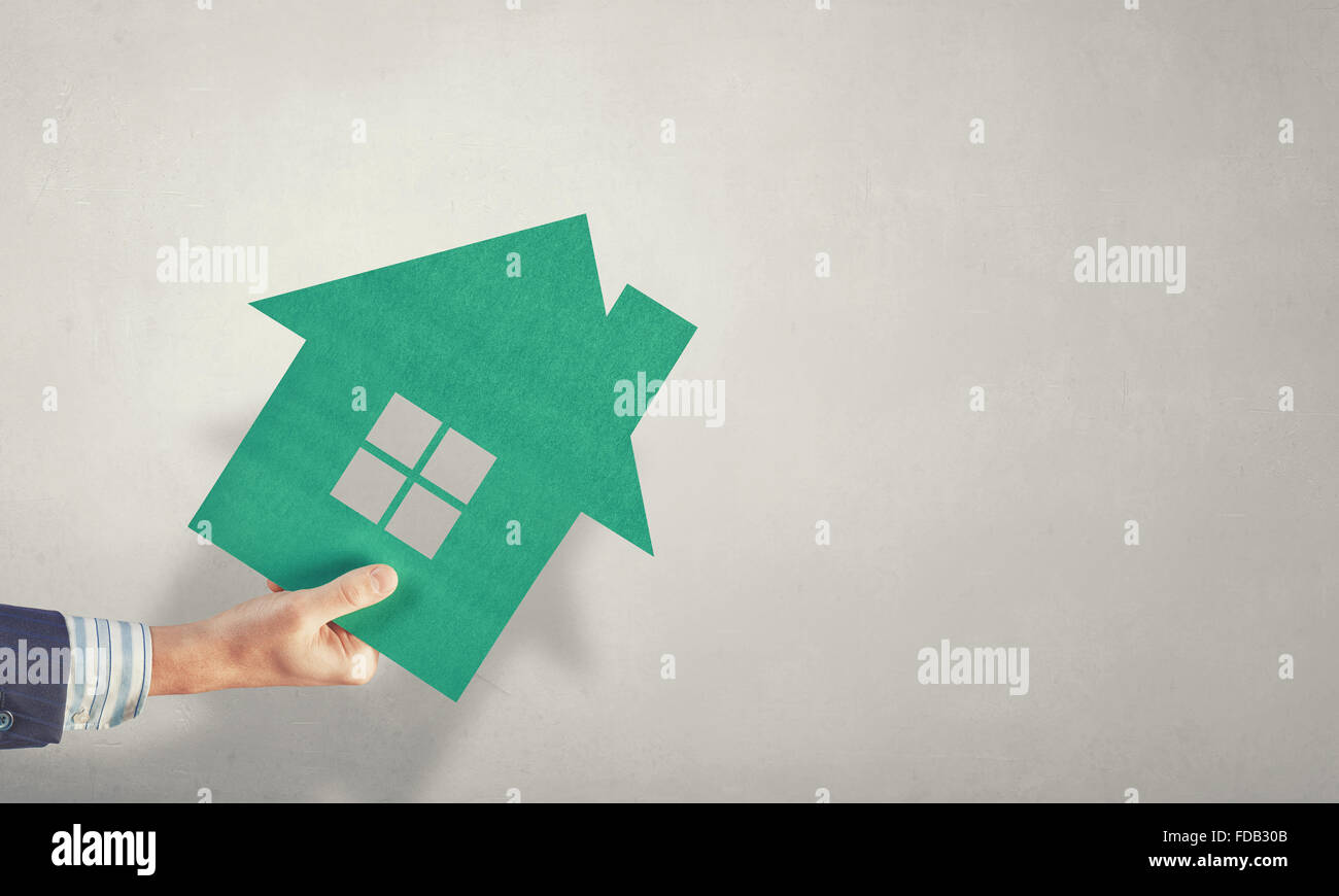 Hand of business person holding house card Stock Photo - Alamy