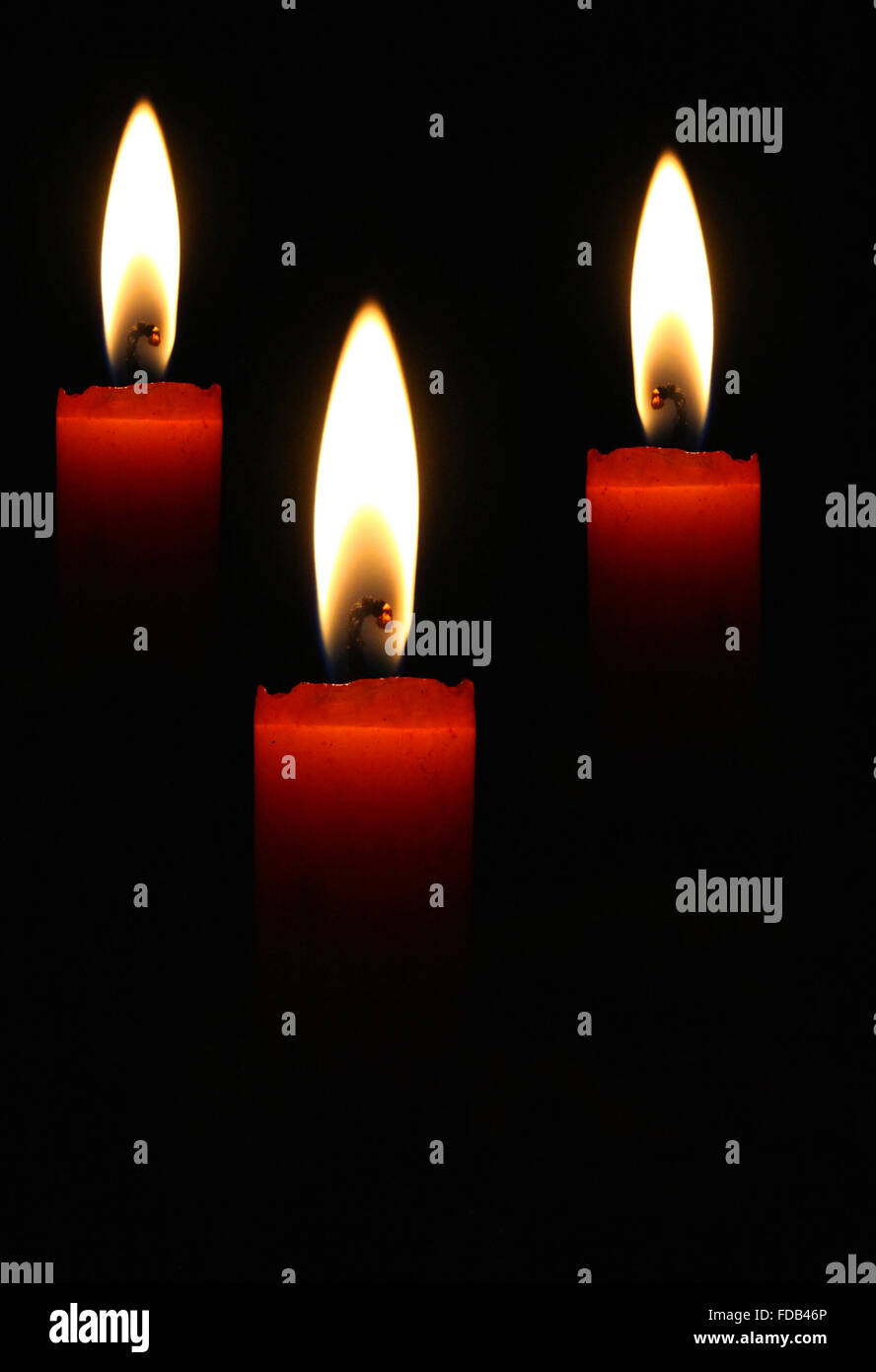 Three blazing candles on a black background Stock Photo - Alamy