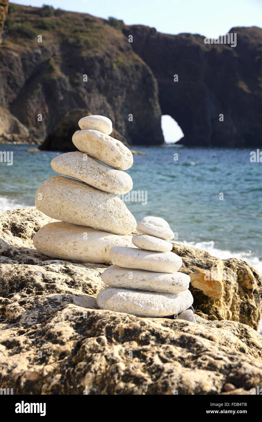 Stacks of stones on the beach with Diana's grotto on a background. Crimea, Black sea, Ukraine Stock Photo