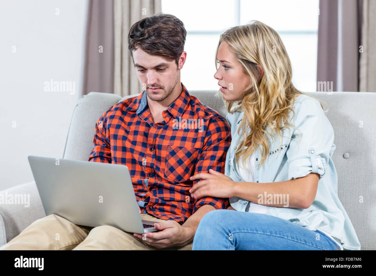 Couple using laptop on the couch Stock Photo - Alamy