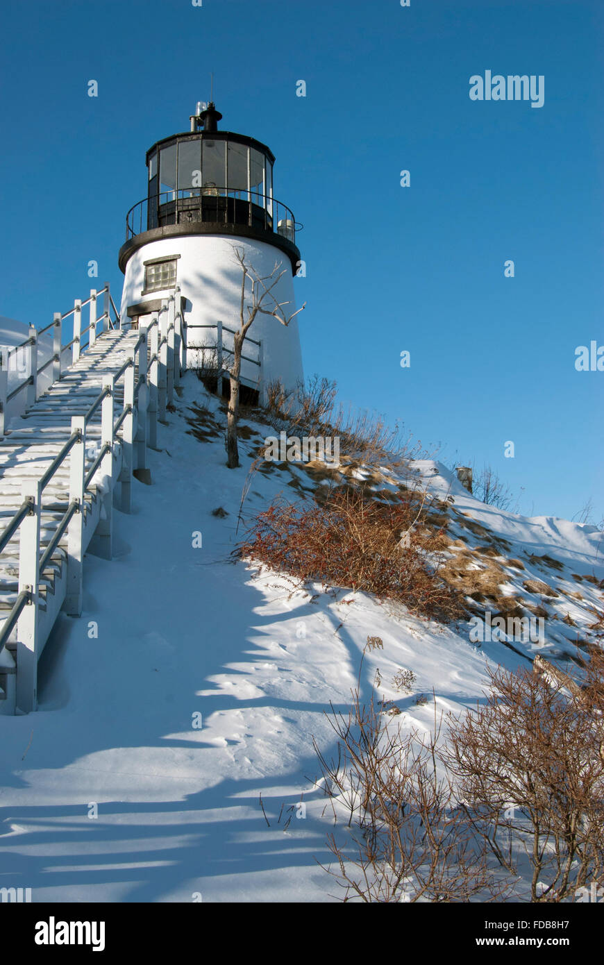 Historic Owls Head Lighthouse sits on a snow covered cliff in Maine