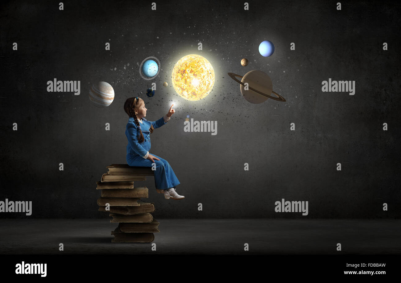 Little girl sitting on stack of books and touching planet Stock Photo ...
