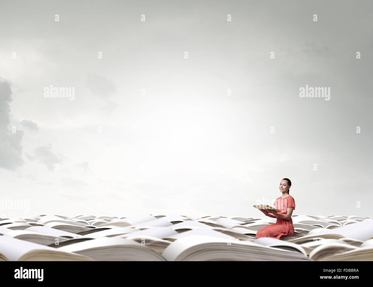 Young girl sitting on stack of books and reading Stock Photo - Alamy