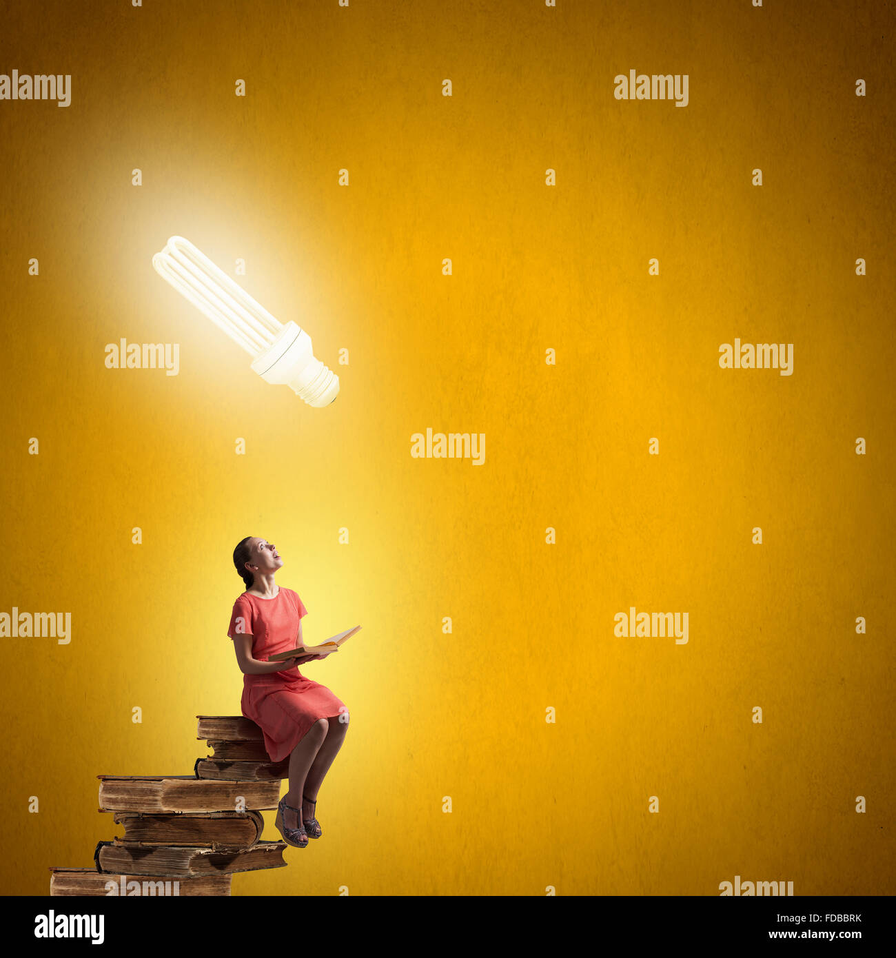 Young girl sitting on stack of books and reading Stock Photo - Alamy