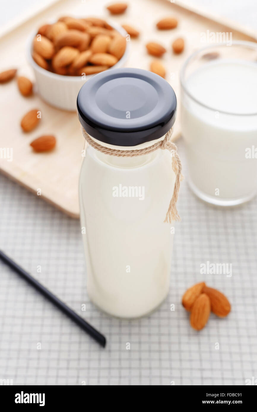 Almond milk in bottle with almonds on table Stock Photo Alamy