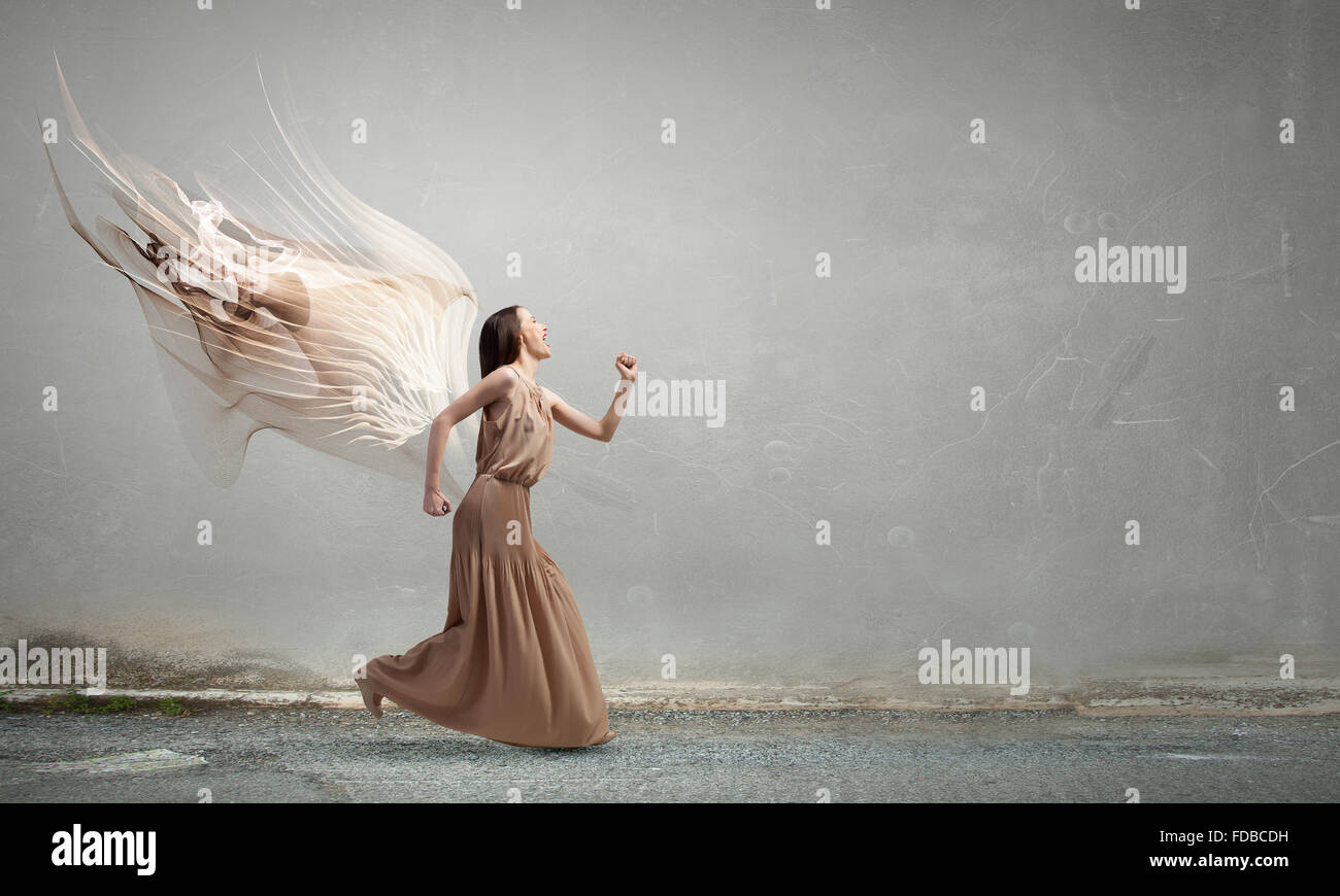 Attractive woman running with angel wings behind back Stock Photo - Alamy